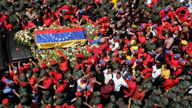 People walk alongside the flag-draped coffin containing the body of Venezuela's late President Hugo Chavez from the hospital where he died, to a military academy where it will remain until his funeral in Caracas, Venezuela, Wednesday, March 6, 2013.