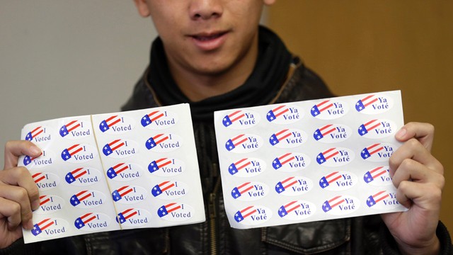 PHOTO:&nbsp;Student clerk Tua Her offers stickers to voters at a fire station in Stockton, Calif. Young voters who are less likely to be engaged in other election cycles are being credited with making the difference this year in California