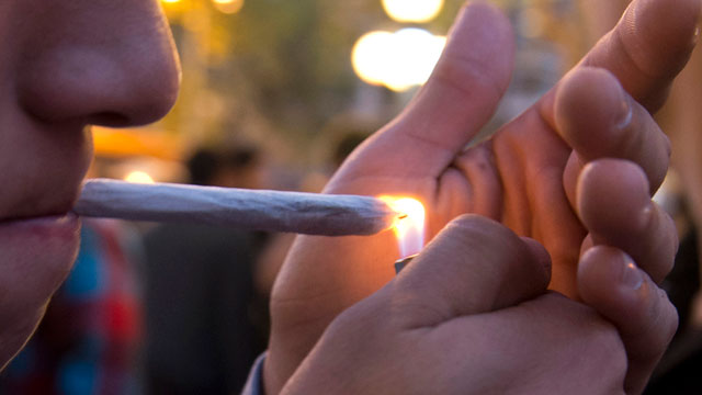 PHOTO: A young man lights a marijuana cigarette during a demonstration demanding a new law on cannabis in Montevideo on May 8, 2013.