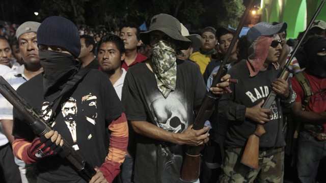 PHOTO:&nbsp;Hooded men stand guard while passing detainees to the Government of the State of Guerrero by the communitarian police at the central square of Ayutla de los Libres, on Febrary 8, 2013. On Tuesday, a final batch of 39 detainees was released.