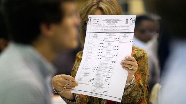 This Oct. 23, 2012 photo shows a county election worker checking an absentee ballot at the Post Beach county election board office in Riviera Beach, Fla. Because of a printing error, somewhere around 27,000 absentee ballots already cast by voters are bein