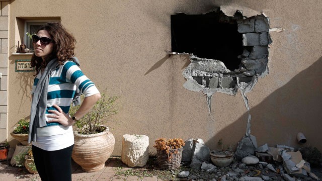An Israeli woman stands outside a damaged house hit by a rocket fired from the Gaza Strip that hit a house near the Israel-Gaza border, Friday, Nov. 16, 2012.