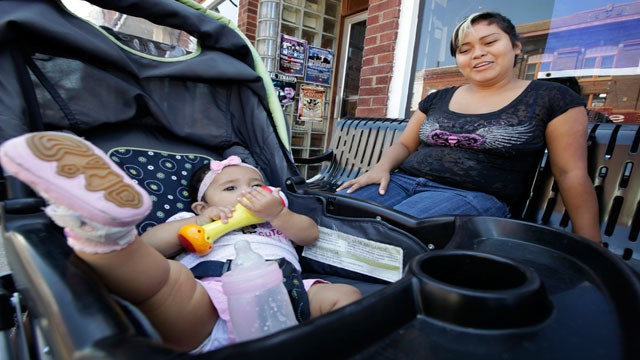 Erika Reyes sits with her seven-month-old daughter on Main Street, Wednesday, Aug. 22, 2012, in West Liberty, Iowa.