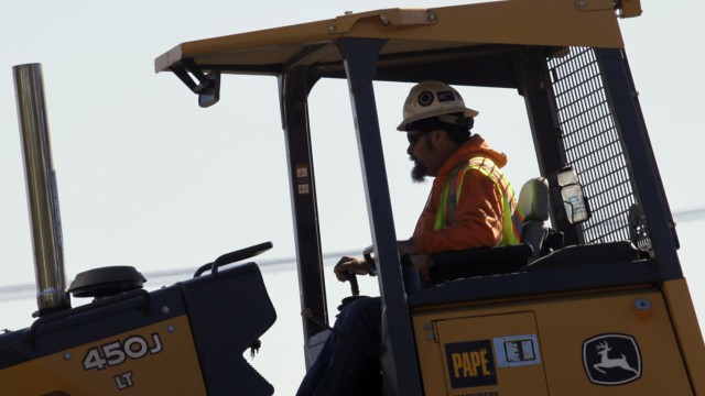 A worker runs a bulldozer on a light rail bridge construction project over the Willamette River in Portland, Ore., Friday, Oct. 5, 2012. Hispanics and blacks still suffer higher unemployment and underemployment.