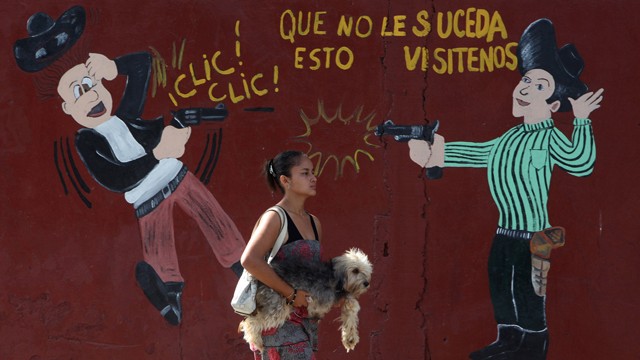 PHOTO: A woman carries her dog past an armory shop in San Pedro Sula, Honduras. Honduras has more homicides than any other country in the world with 91 per 100,000 people, the World Health Organization says.