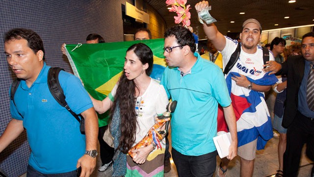 Cuban dissident blogger Yoani Sanchez, center, is chanted at by pro-Castro supporters, accusing her of being a U.S. spy, upon her arrival at the Guararapes International airport, in Recife, Brazil, Monday, Feb.18, 2013.