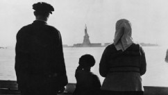 PHOTO: An immigrant family on Ellis Island looking across New York Harbor at the Statue of Liberty.