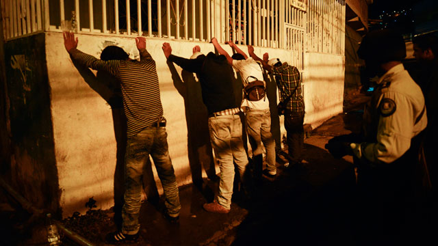 PHOTO: Municipal police officers make a routine check on passers-by as they patrol the streets and alleys of the impoverished Petare neighbourhood, one of Caracas' most dangerous slums.
