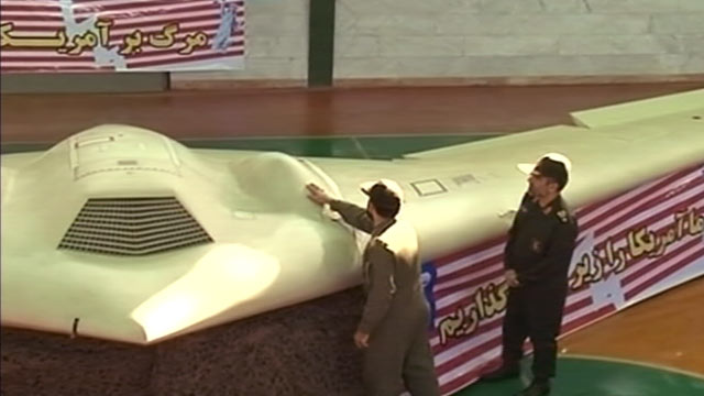 PHOTO: A military official gives a tour of an intact RQ-170 drone in a hangar to another Iranian military official.
