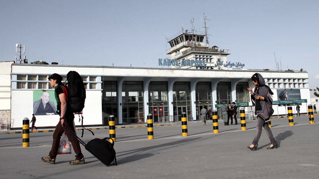 PHOTO: Passengers walk beside a portrait of Afghan President Hamid Karzai at Kabul International Airport, in Kabul, Afghanistan, March 26, 2012.