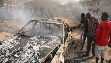PHOTO: Men look at the wreckage of a car following a bomb blast at St Theresa Catholic Church outside the Nigerian capital Abuja, Dec. 25, 2011.