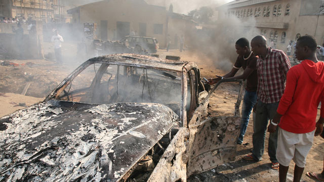 PHOTO: Men look at the wreckage of a car following a bomb blast at St Theresa Catholic Church outside the Nigerian capital Abuja, Dec. 25, 2011.