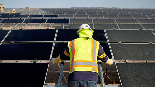 PHOTO: A worker installs First Solar Inc. photovoltaic solar panels at the Agua Caliente Solar Project in Yuma County, Arizona, U.S., Feb. 16, 2012.