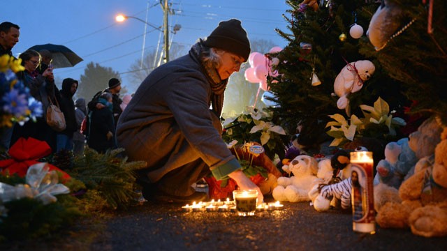 PHOTO: Tracy Kirk re-lights candles at a memorial near the Newtown Firehouse, Dec. 16, 2012, in Newtown, Conn.