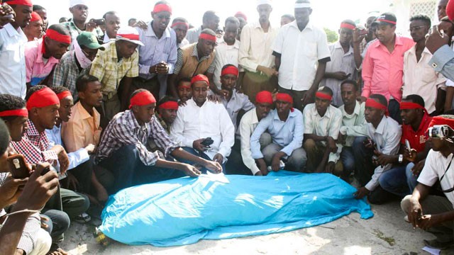 PHOTO: Fellow journalists crowd around the body of Abdisalam Hiis who was murdered in Mogadishu on December 18, 2011.