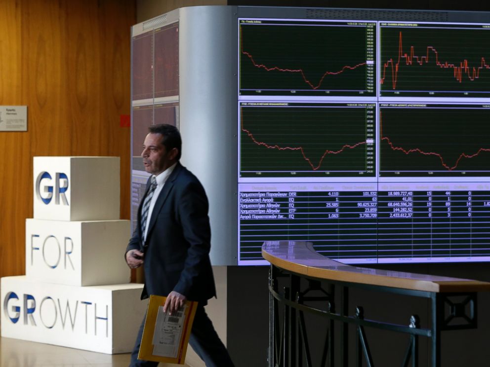 PHOTO: An employee of the Stock Exchange walks next to a display showing stock price movements in Athens, Dec. 29, 2014.