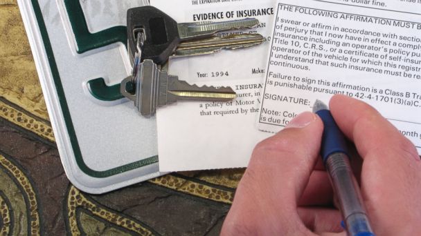 PHOTO: A man signs car insurance forms.