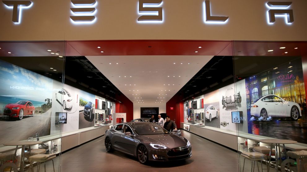 PHOTO: People look at a Tesla Motors vehicle on the showroom floor at the Dadeland Mall in Miami, Fla., Feb. 19, 2014.