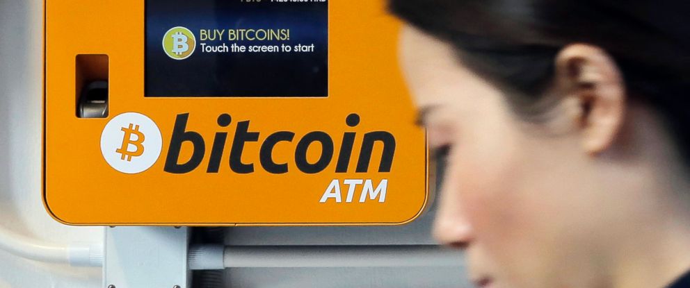 FILE - In this Dec. 21, 2017 file photo, a woman walks past the Bitcoin ATM in Hong Kong.