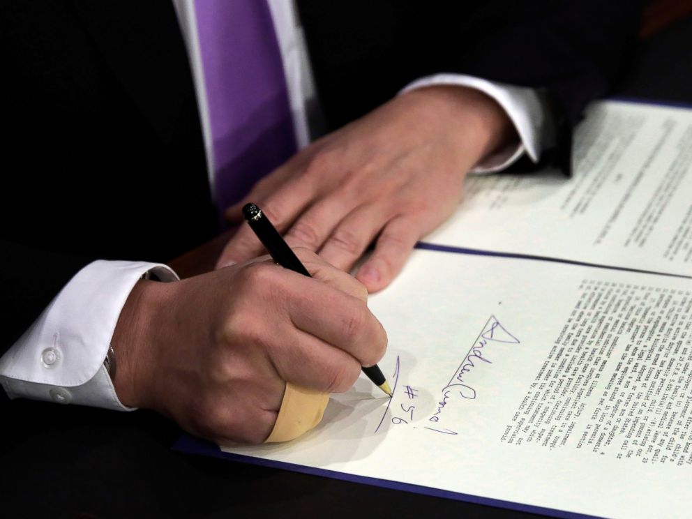 PHOTO: New York Gov. Andrew Cuomo, signs a law that will gradually raise New Yorks minimum wage to $15, at the Javits Convention Center, in New York, April 4, 2016.