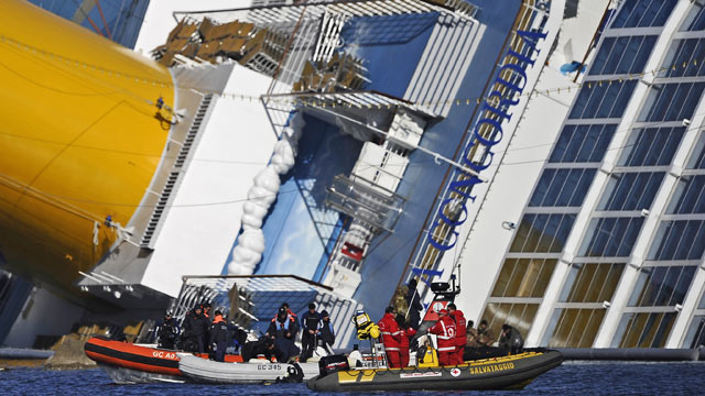 PHOTO: Rescue workers stand in small boats near the stricken cruise liner Costa Concordia lying aground in front of Giglio island, Jan. 26, 2012.
