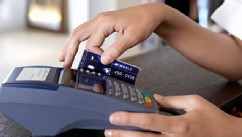 PHOTO: Young female shop assistant using credit card machine.