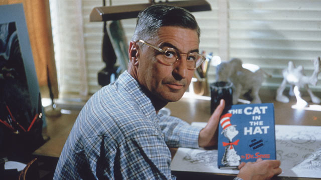 PHOTO: Theodor Seuss Geisel sits at his drafting table in his home office with a copy of his book, 'The Cat in the Hat', La Jolla, California, April 25, 1957.