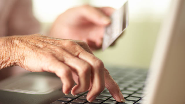 PHOTO: Close-up of Senior womans hands using laptop and holding a credit card.