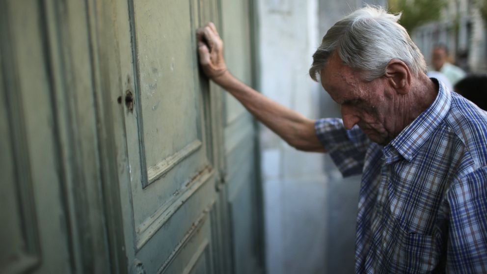 PHOTO: A senior citizen leans against the door of a closed bank as he queues up to collect his pension outside a National Bank of Greece branch in Kotzia Square, July 7, 2015 in Athens, Greece.