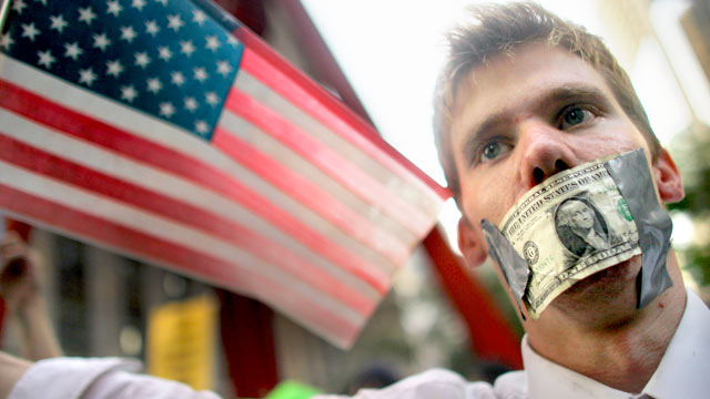 PHOTO: A protester wears a dollar bill over his mouth at the start of a march by demonstrators opposed to corporate profits on Wall Street on Sept. 30, 2011 New York City.