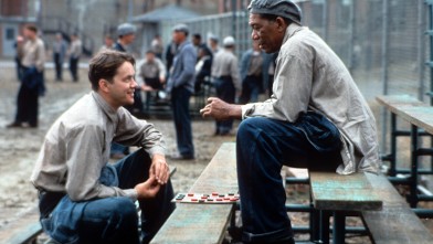 PHOTO: Tim Robbins and Morgan Freeman sitting outside on the benches playing checkers and talking in a scene from the film 'The Shawshank Redemption'.