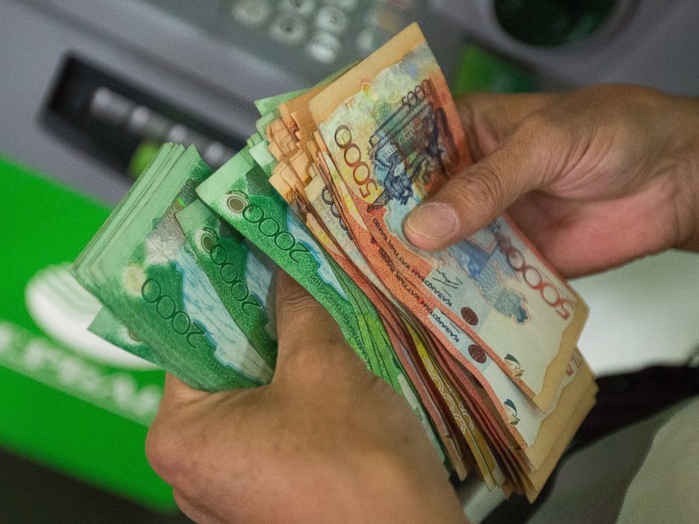 PHOTO: A customer counts tenge currency banknotes inside a bank in Almaty, Kazakhstan, June 23, 2015.