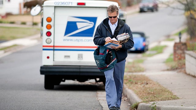 PHOTO: U.S. Postal Service city letter carrier Roy Sipe delivers mail to homes in Fairfax, Virginia, U.S., Nov. 30, 2011.