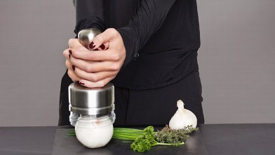 A young woman is shown using an onion chopper.