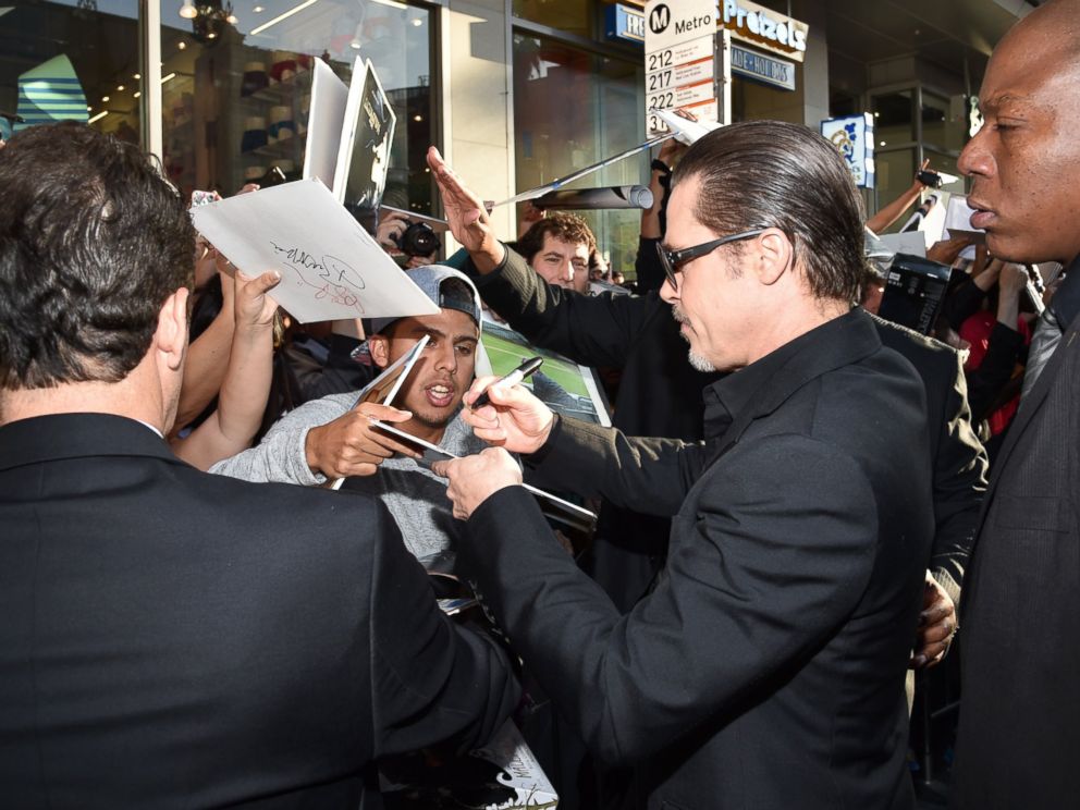 PHOTO: Brad Pitt signs autographs at the world premiere of Maleficent at the El Capitan Theatre, May 28, 2014 in Los Angeles.