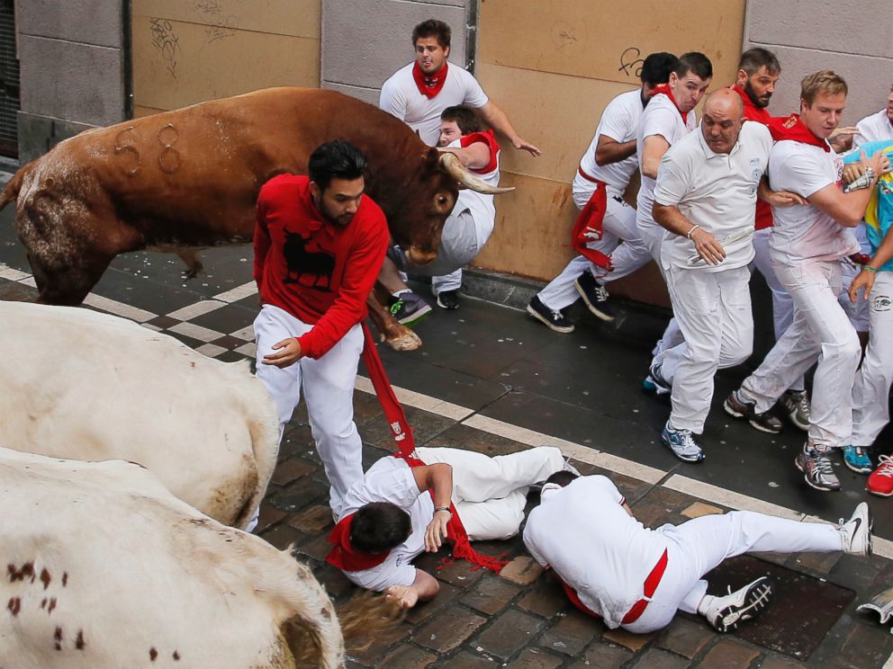 PHOTO: A reveler is tossed by a Miura fighting bull as other fall during the running of the bulls at the San Fermin festival, in Pamplona, Spain, on July 14, 2014.