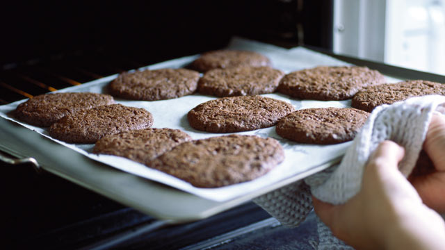 PHOTO: A woman takes a sheet of cookies out of the oven.