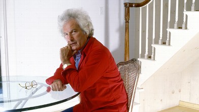 PHOTO: Portrait of American author Joseph Heller (1923 - 1999) as he sits at a glass-topped table near a staircase in his Long Island home, New York, 1985.