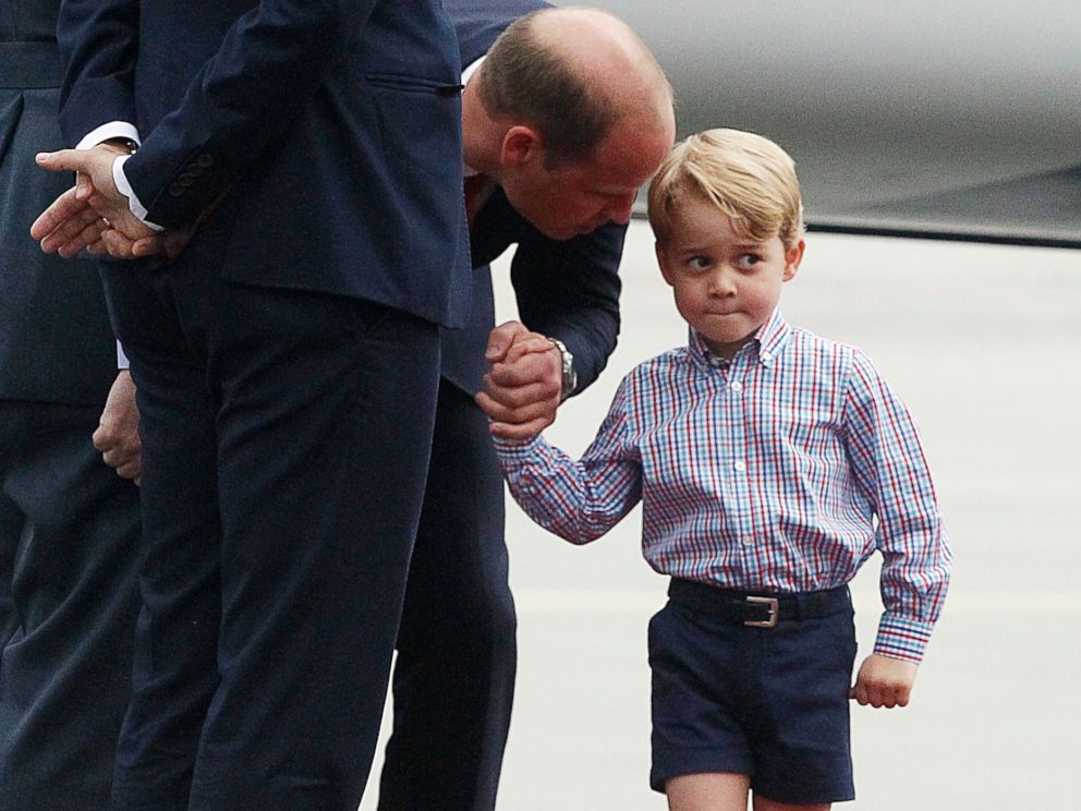 PHOTO: Britains Prince William, left, holds the hand of his son Prince George on arrival at the airport, in Warsaw, Poland, July 17, 2017.