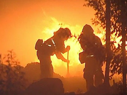A Picture of two fire fighters in front of flames.