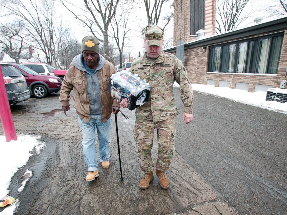 PHOTO: Michigan National Guard Staff Sergeant Steve Kiger helps a Flint resident take bottled water out to his car, Jan. 13, 2016 in Flint, Michigan.