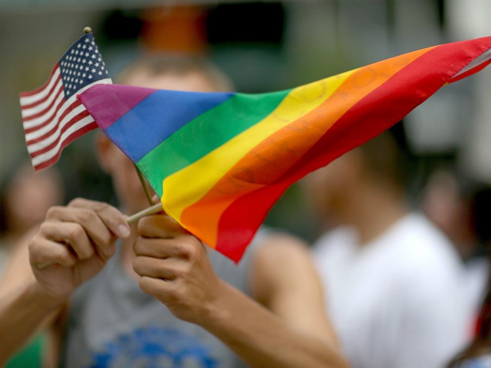PHOTO: A protester holds an American flag and rainbow flag in front of the Miami-Dade Courthouse to show his support of the LGBTQ couples, July 2, 2014, in Miami.