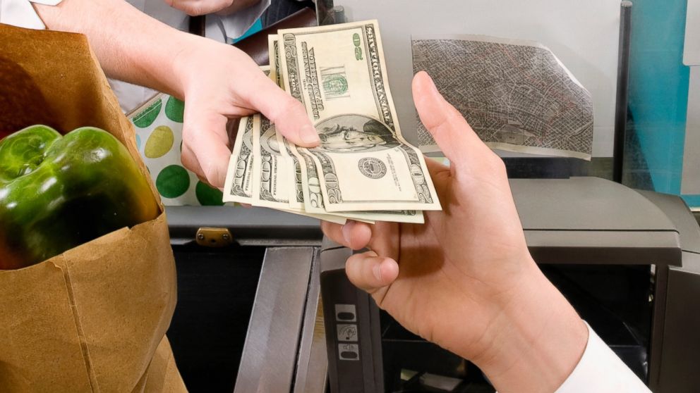 PHOTO: A customer is pictured handing a cashier money in this stock image.