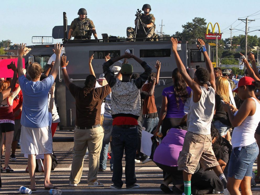 PHOTO: Protesters raise their hands in front of police atop an armored vehicle in Ferguson, Mo. on Aug. 13, 2014.