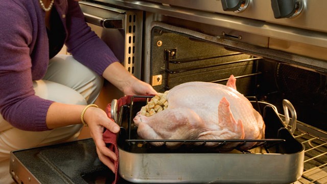 PHOTO: Woman putting stuffed turkey into oven