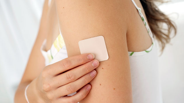 PHOTO: A woman places a nicotine patch on her arm.