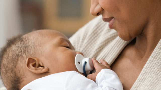 PHOTO: A mother holding her sleeping son with a pacifier.
