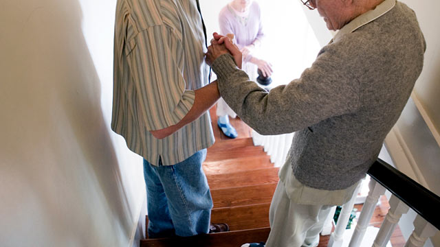 PHOTO: Man helping elderly man down the stairs.