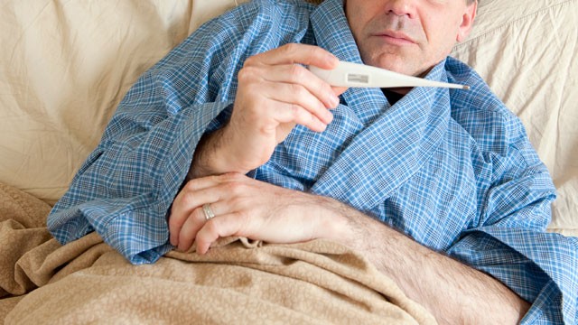 PHOTO: A man lies in bed sick with the flu.