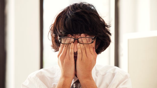 PHOTO: A man rubs his eyes at work.